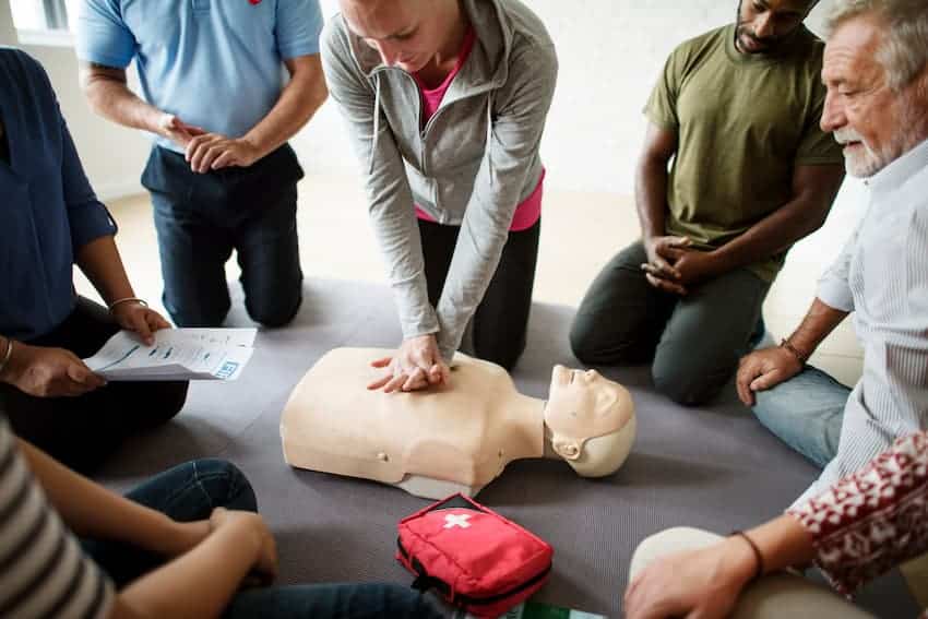 Salariés en formation SST pratiquant un massage cardiaque sur un mannequin lors d’un exercice de premiers secours en entreprise.